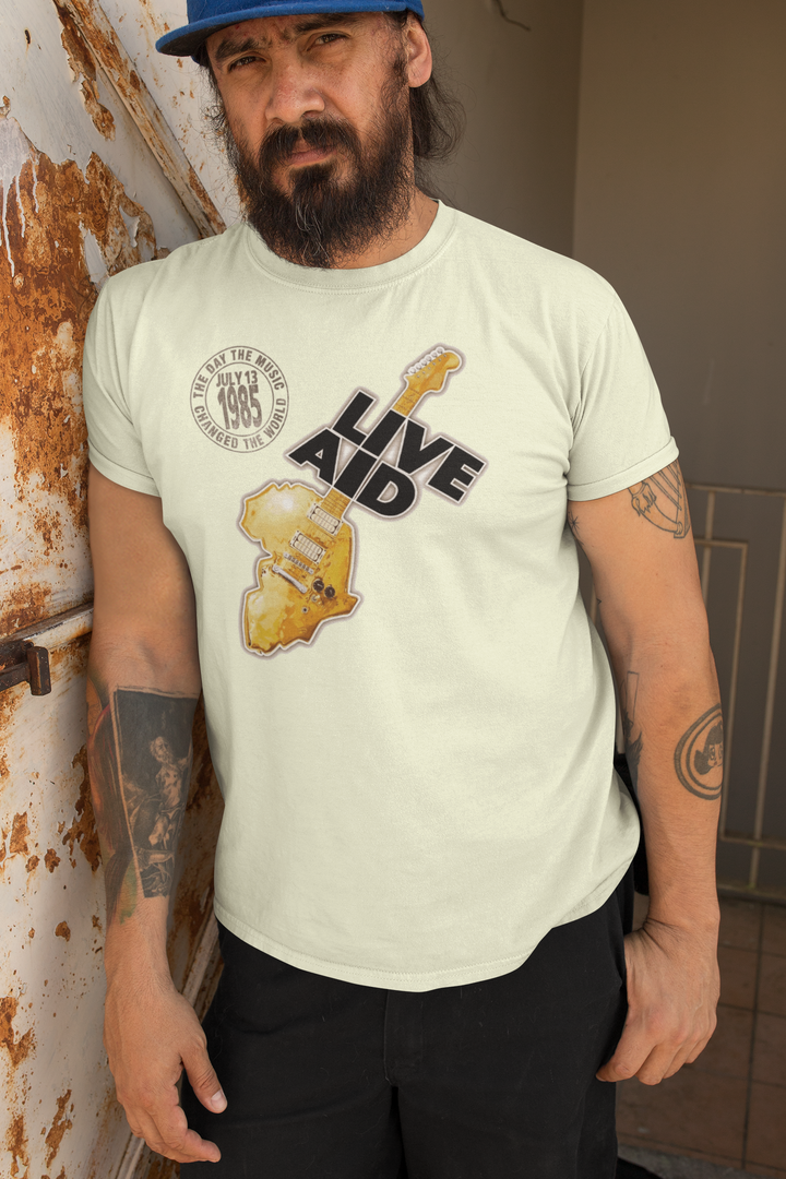 Live Aid was a benefit concert held at Wembly Stadium in London on July 13, 1985. The event grew from the Band Aid single "Do They Know It's Christmas?". That song featured many of the UK's top pop stars and was organized by Bob Geldof of Boomtown Rats and Midge Ure, then of Ultravox. Geldof wore a "Feed The World" T-shirt during the songs recording. All artists took the stage to further raise money for famine relief in Africa. *A portion of proceeds from this t-shirt sale benefits Oxfam.
